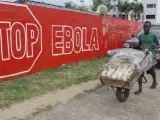 Un hombre lleva pan junto a un muro en con un anuncio de la campaña creada para combatir el brote de ébola en África Occidental, en Monrovia, Liberia.
