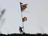 Un joven cuelga una estelada en el mismo palo en el que todavía ondea la bandera rota cerca del monasterio de Sant Pere de Rodes (Girona).