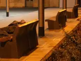Un indigente pasa la noche en un banco de Barcelona.