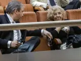La alcaldesa de Madrid, Manuela Carmena, conversa con el socialista Antonio Miguel Carmona, en la tribuna de invitados de la Asamblea de Madrid.