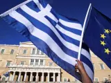 Una bandera griega y otra de la UE, frente al edificio del Parlamento heleno en Atenas, durante una manifestación para exigir que el país continúe en la Eurozona.
