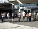 Colas de personas esperando para retirar dinero de cajeros automáticos en una sucursal de Alpha Bank, en Atenas (Grecia).
