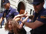 Agentes de la Policía Nacional detienen a una mujer tras la carga contra las protestas del 15-M ante Les Corts Valencianes.