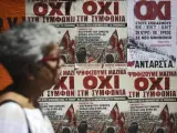 Una mujer pasa delante de varios carteles que piden el voto negativo en el referéndum del próximo domingo, en Atenas.