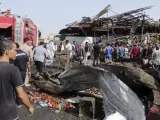 Varias personas caminan por el lugar donde se ha producido un atentado en un mercado en Bagdad (Irak). El grupo terrorista Estado Islámico (EI) asumió la autoría delAtentado con camión bomba que causó al menos 55 muertos y 110 heridos en un mercado popular en el barrio de Ciudad Sadr, en el este de Bagdad.