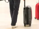 Pasajeros en un aeropuerto con equipaje de mano.