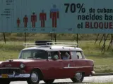 Un vehículo circula por una carretera en La Habana donde puede leerse un cartel referente al número de cubanos que han nacido bajo el bloqueo.