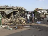 Varias personas observan el lugar de un ataque suicida con bomba en un mercado en Maiduguri, Nigeria, cometido supuestamente por Boko Haram.