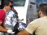 Oficiales de la Guardia Costera desembarcan a un niño inmigrante envuelto en una manta térmica en el puerto de Mytilini, en la isla de Lesbos (Grecia). Dos personas que viajaban en la misma embarcación neumática, una mujer de 35 años y un menor de 2, fallecieron antes de llegar a tierra.