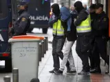 Dos efectivos de la Policía acompañan a una persona detenida en el madrileño barrio de Vallecas acusada de formar parte de un grupo vinculado al Estado Islámico.
