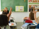 Varios niños con las manos levantadas durante una clase.