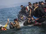 Varios hombres saltan al agua desde una lancha neumática tras alcanzar las costas de la isla griega de Lesbos.