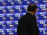 Un hombre pasa por delante de una pantalla que refleja el índice Nikkei de la Bolsa de Valores de Tokio.