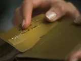 Una mujer saca de la cartera su tarjeta de crédito.