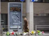 Una mujer camina junto a la entrada de la estación de metro de Maalbeek, decorada con ramos de flores, en Bruselas.