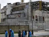 Un grupo de trabajadores ucranianos pasa por delante de la central nuclear de Chern&oacute;bil.
