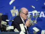 El presidente de la FIFA, Joseph Blatter, bajo una lluvia de billetes que le lanzó el humorista británico Simon Brodkin, durante una rueda de prensa para presentar los resultados de la reunión del Comité Ejecutivo de la FIFA en su sede de Zúrich, Suiza, en julio de 2015.