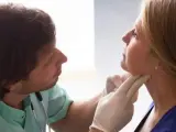 Un médico explora la garganta de una paciente.