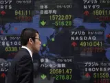 Un hombre camina frente a un tablero informativo del índice del mercado bursátil japonés en Tokio.