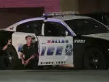 Varios agentes se protegen de los disparos tras un coche patrulla, durante un violento tiroteo que se produjo la noche de este jueves en Dallas (EE UU).
