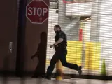 Un agente corre para protegerse de los disparos, en un tiroteo que se ha producido en Dallas (EE UU) durante una protesta contra la violencia policial hacia los negros.