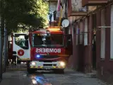 Un camión de los bomberos trabajando en la calle donde se ha producido el incendio.