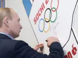 El presidente ruso Vladimir Putin estampa su firma en una pared durante su visita a un centro de entrenamiento para voluntarios de los Juegos Olímpicos de Invierno de Sochi, Rusia.