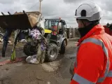 Uno de los trabajadores utiliza una excavadora para tirar las tiendas y casas de madera (con palés) de la parte sur de la jungla de Calais.