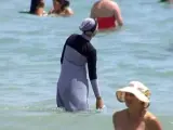 Una mujer viste un burkini en una playa.