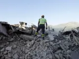 Un bombero de Amatrice, sobre un montón de escombros de un edificio derrumbado tras el terremoto.