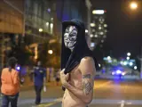Una manifestante protesta, con una careta de V de Vendetta, en el centro de Charlotte, Carolina del Norte (EE UU). Cientos de personas marcharon en la tercera noche de protestas raciales pese a que rige un toque de queda decretado después de la muerte del hombre herido de bala.