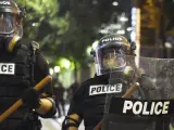 Policías antidisturbios permanecen en guardia durante la noche de enfrentamientos en la ciudad de Charlotte.