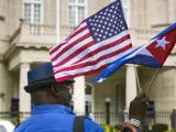 Un hombre lleva banderas de Cuba y EE UU.