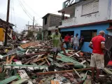 Varios cubanos intentan recuperar sus pertenencias entre los destrozos causados por el paso del huracán Matthew, al paso por la localidad de Baracoa.
