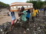 Varios hombres cargan un ataúd e intentan cruzar el río La Digue, debido al derrumbe del único puente que conecta con el sur, tras el paso del huracán Matthew por Haití.
