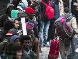Varios migrantes esperan una cola en el centro de recepción de corta estancia en el campamento conocido como 'La Jungla' durante su desmantelamiento en Calais (Francia).