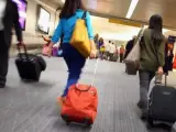Pasajeros con sus maletas en los pasillos de un aeropuerto.