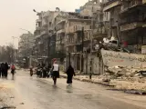 Varias personas caminan por las calles del barrio de al-Mashad en la zona controlada por los rebeldes en Alepo (Siria).