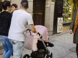 Una pareja pasea junto a su bebé en carrito.
