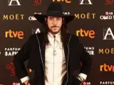 El actor Óscar Jaenada llamó la atención en el photocall de los Goya 2016 por su curioso estilismo con sombrero de ala ancha, abrigo negro y botines altos.