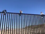 Gente que ha escalado el muro fronterizo.