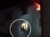 Un bombero en el momento de rescatar al vuelo a una adolescente que se había lanzado del piso superior que estaba siendo pasto de las llamas.