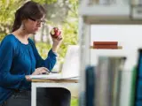 Una chica come una manzana mientras trabaja.
