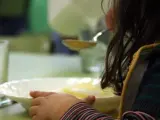 Una niña toma el almuerzo en un comedor escolar.