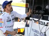 El piloto español Fernando Alonso (i) mira un monitor previo a su entrenamiento libre para las 500 Millas de Indianápolis.