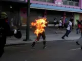 Un joven corre por una calle de Caracas (Venezuela), tras ser rociado y prendido fuego en una manifestación.