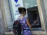 Una mujer saca dinero en un cajero automático.