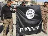 Soldados de las fuerzas especiales iraquíes sujetan una bandera del Estado Islámico en la ciudad de Bartila, Irak.