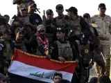 Soldados iraquíes sostienen una bandera de Irak en el centro de Mosul, tras la liberación de la ciudad del control del grupo Estado Islámico.