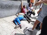 Dos mujeres yacen en el suelo durante un enfrentamiento entre un grupo de personas adeptas al oficialismo y personas opositoras al gobierno nacional durante la consulta popular.